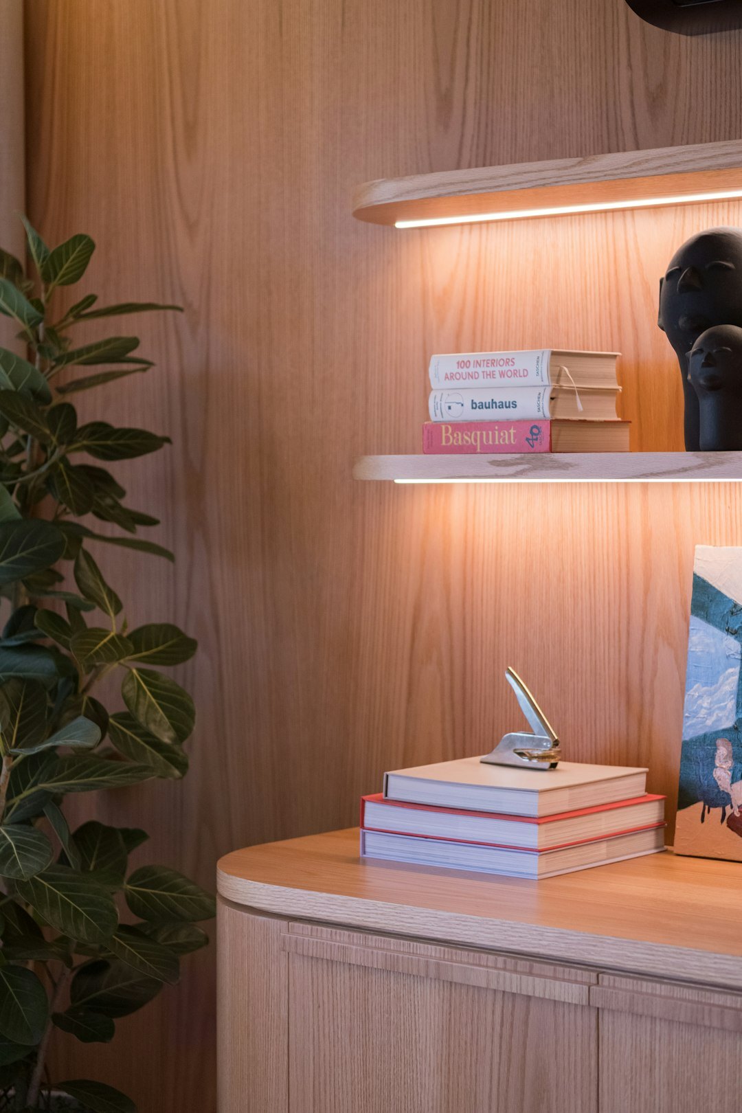 Stack of hardcover books with a magnifying glass and coffee cup on a wooden desk